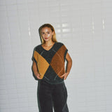 Model i beige harlekin vest med V-udskæring fra WithBlack, set forfra med vide mørke bukser
