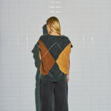 Model i langhåret harlekin vest i beige, brun og grå fra WithBlack, set bagfra