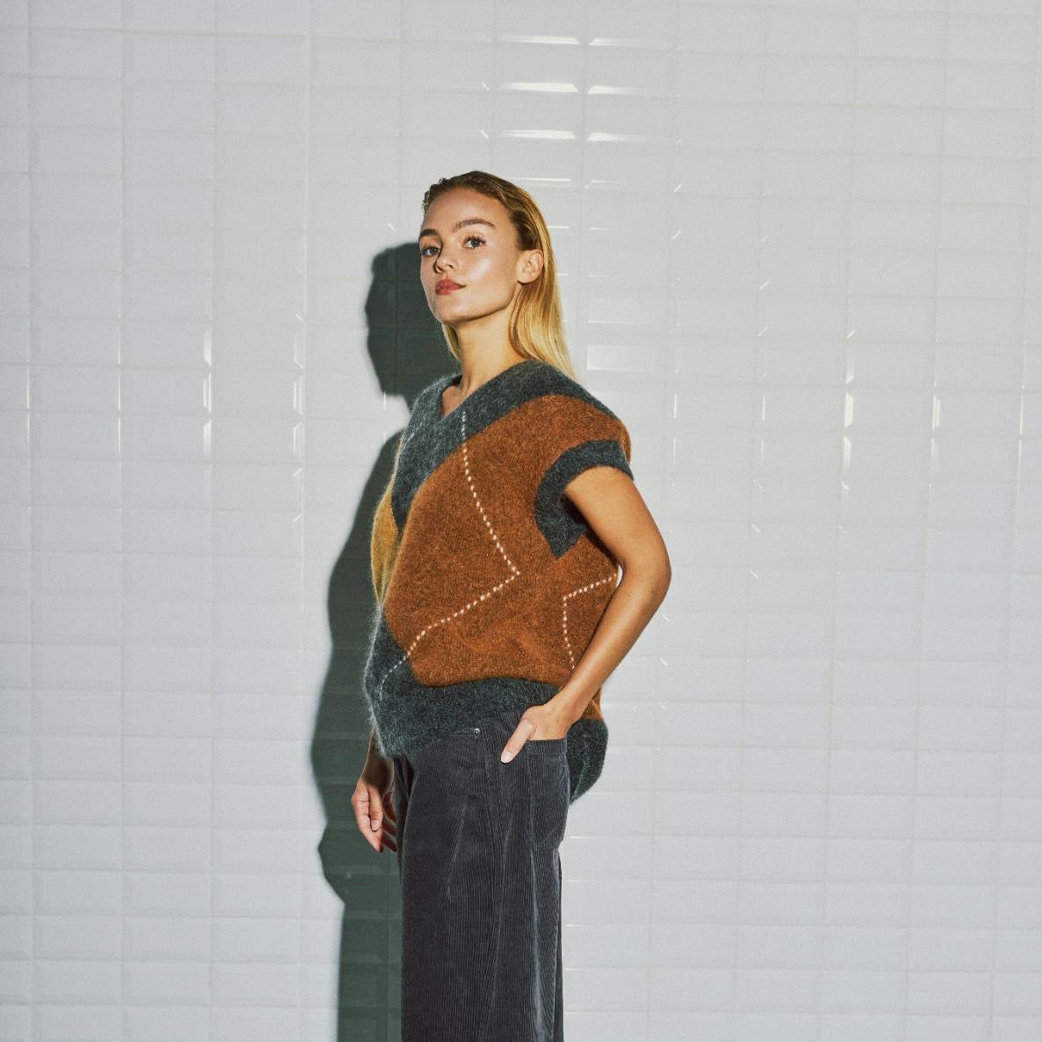 Model i harlekin vest fra WithBlack set skråt fra siden med det brune felt og ribkant
