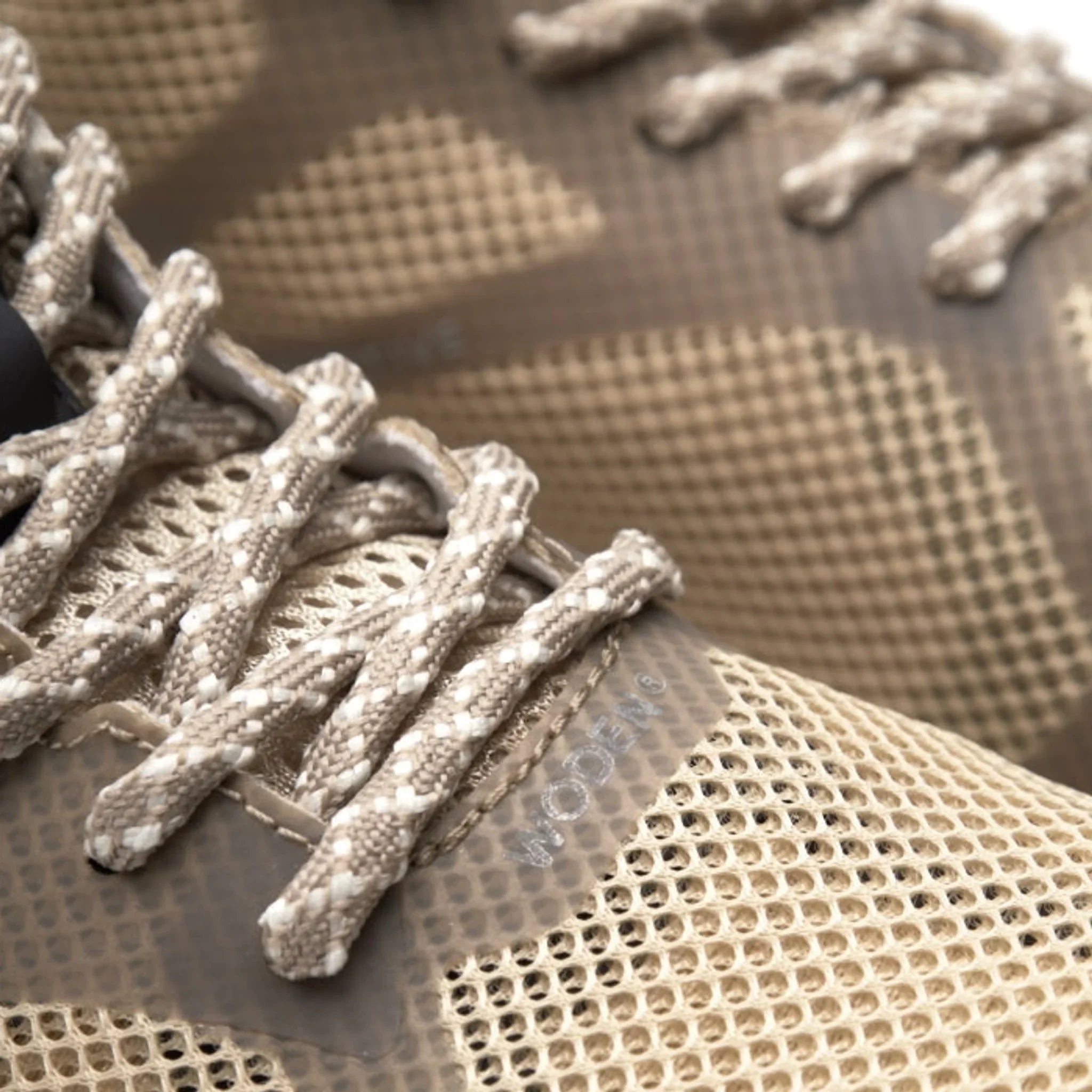 Nærbillede af mesh-overdel og melerede snørebånd på beige Woden sneakers