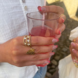 Guldfarvet Crystal Ring fra Wolff Jewelry med klare sten båret på en hånd, der holder et glas