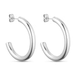 Sølvfarvede Emmi Hoops øreringe på 30 mm i kirurgisk stål med ørestikker, set fra siden på lys baggrund