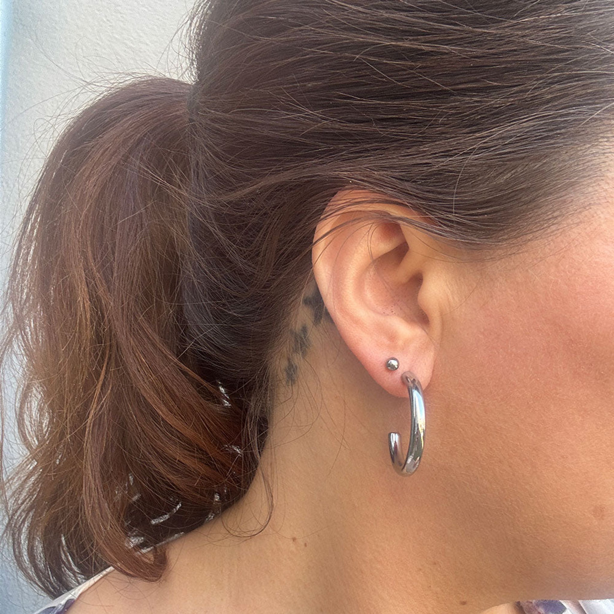 Sølvfarvet Emmi Hoops ørering på 30 mm båret i øret på model med hestehale, set fra siden