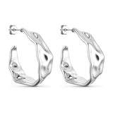 Fanny Hoops sølv øreringe fra Wolff Jewelry, brede creoler med bølget overflade, set fra siden på hvid baggrund