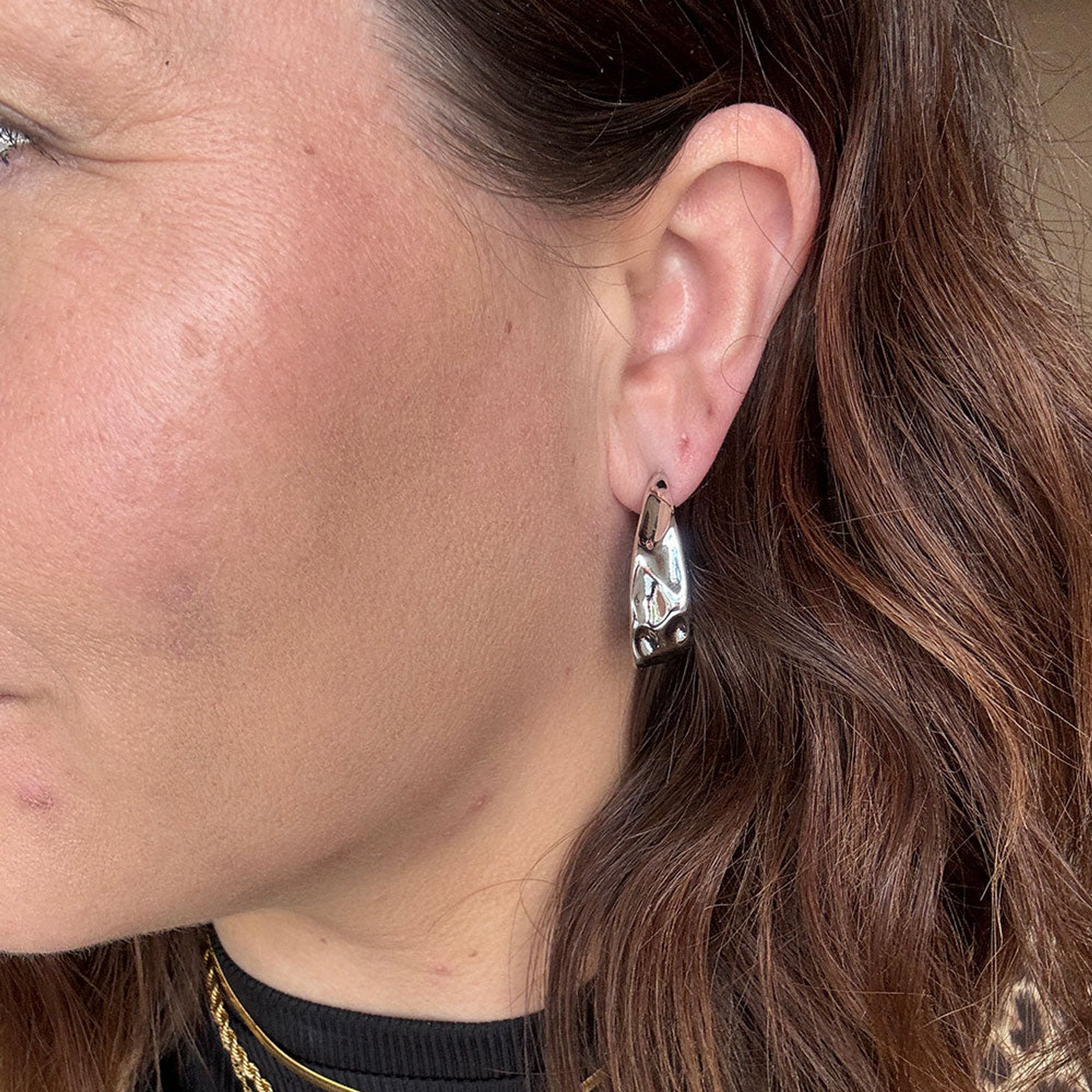 Fanny Hoops sølv ørering med bølget overflade båret i øret, tæt på