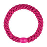 Pink flettet hårelastik i farven Hot Pink med blank pink perle, set ovenfra på lys baggrund