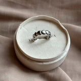 Sølvfarvet ring med en række små hjerter fra Wolff Jewelry i en hvid rund smykkeæske