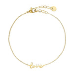 Guldfarvet armbånd Luna Love fra Wolff Jewelry med ordet love i skråskrift og karabinlås, set ovenfra på lys baggrund
