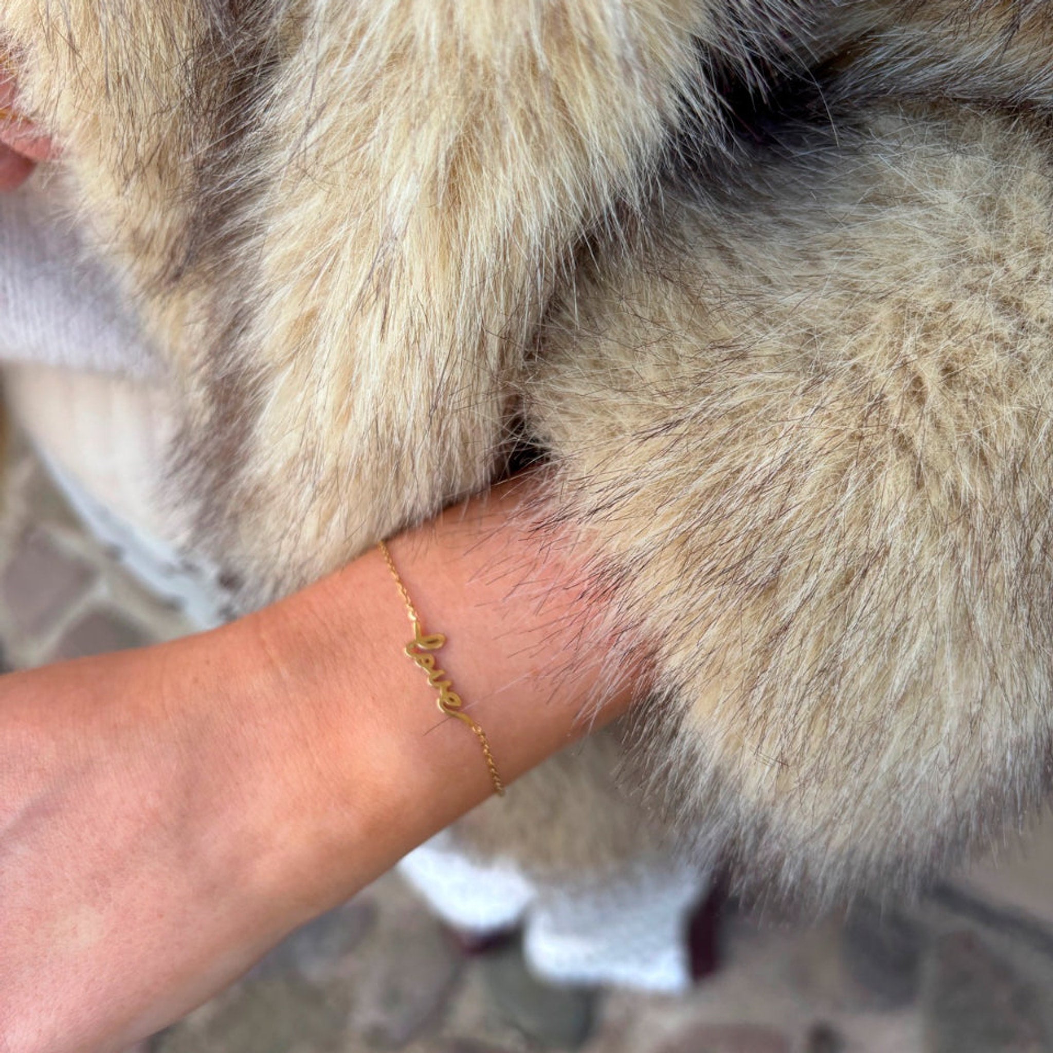 Guldfarvet Luna Love armbånd med love-skrift båret om håndleddet