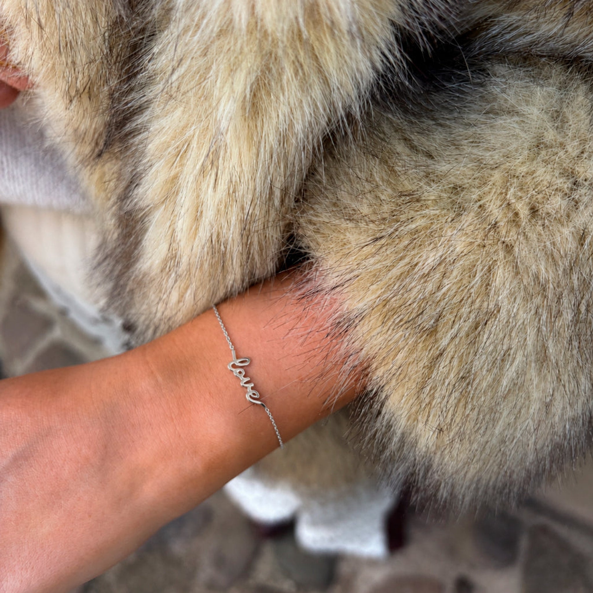 Sølvfarvet love-armbånd båret på håndleddet, set tæt på