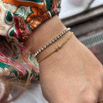 Guldfarvet MOR armbånd fra Wolff Jewelry på håndled, stakket med et andet armbånd