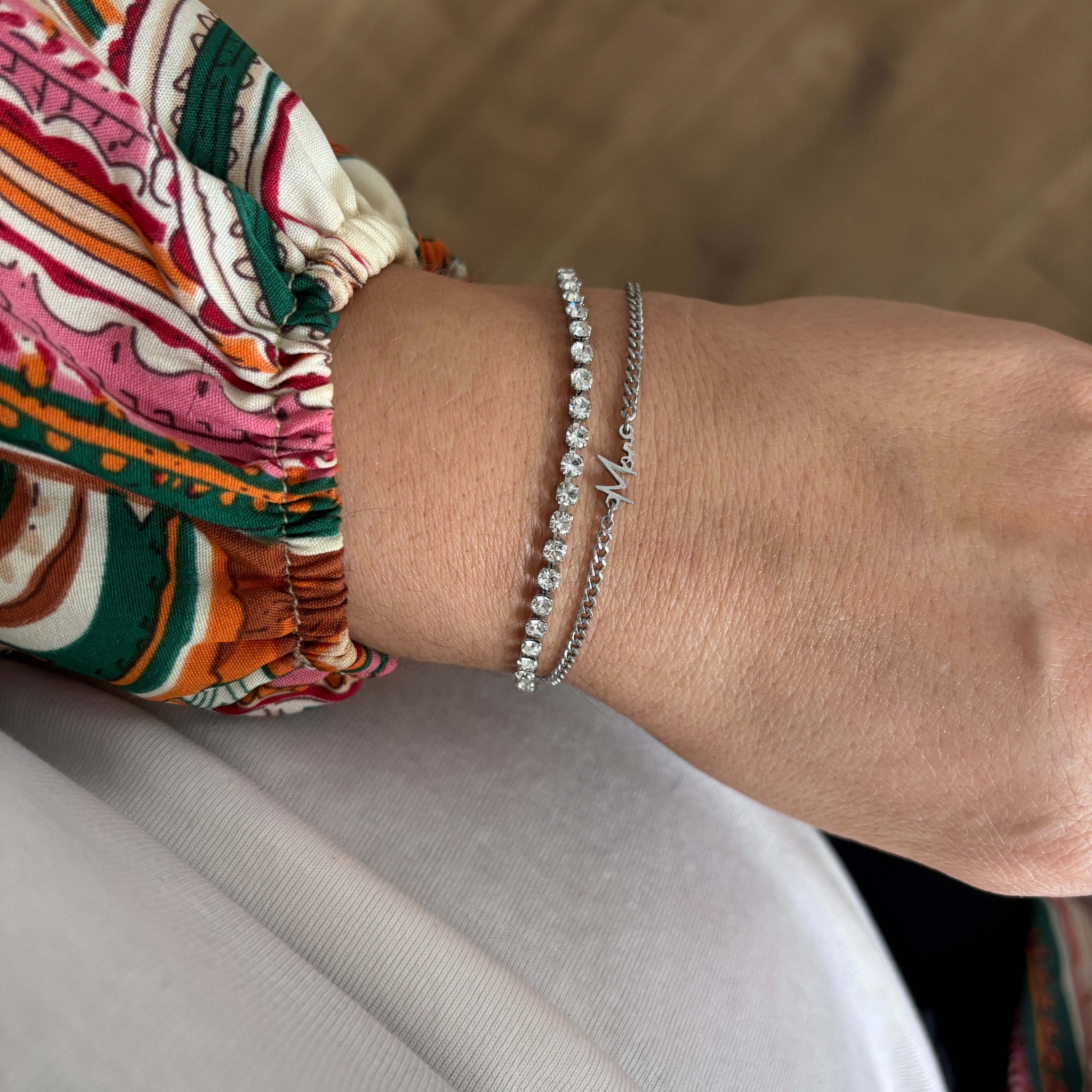 Sølvfarvet Mor-armbånd på håndleddet, stylet med et armbånd med sten og en mønstret bluse