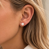 Ørering med hvid perle fra Wolff Jewelry båret i øret på model med lyst hår, tæt på