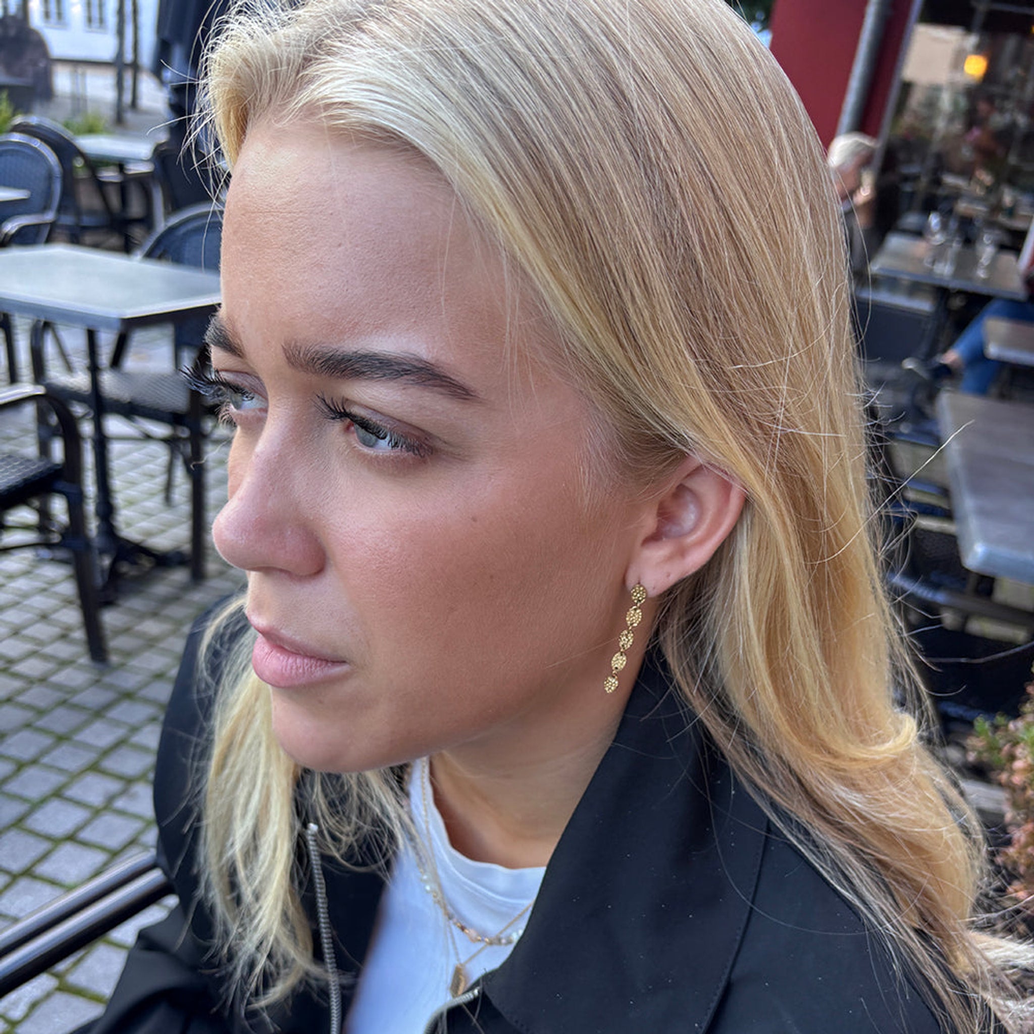 Model med lyst hår bærer guldfarvet Rustic Earring fra Wolff Jewelry, set fra siden i profil