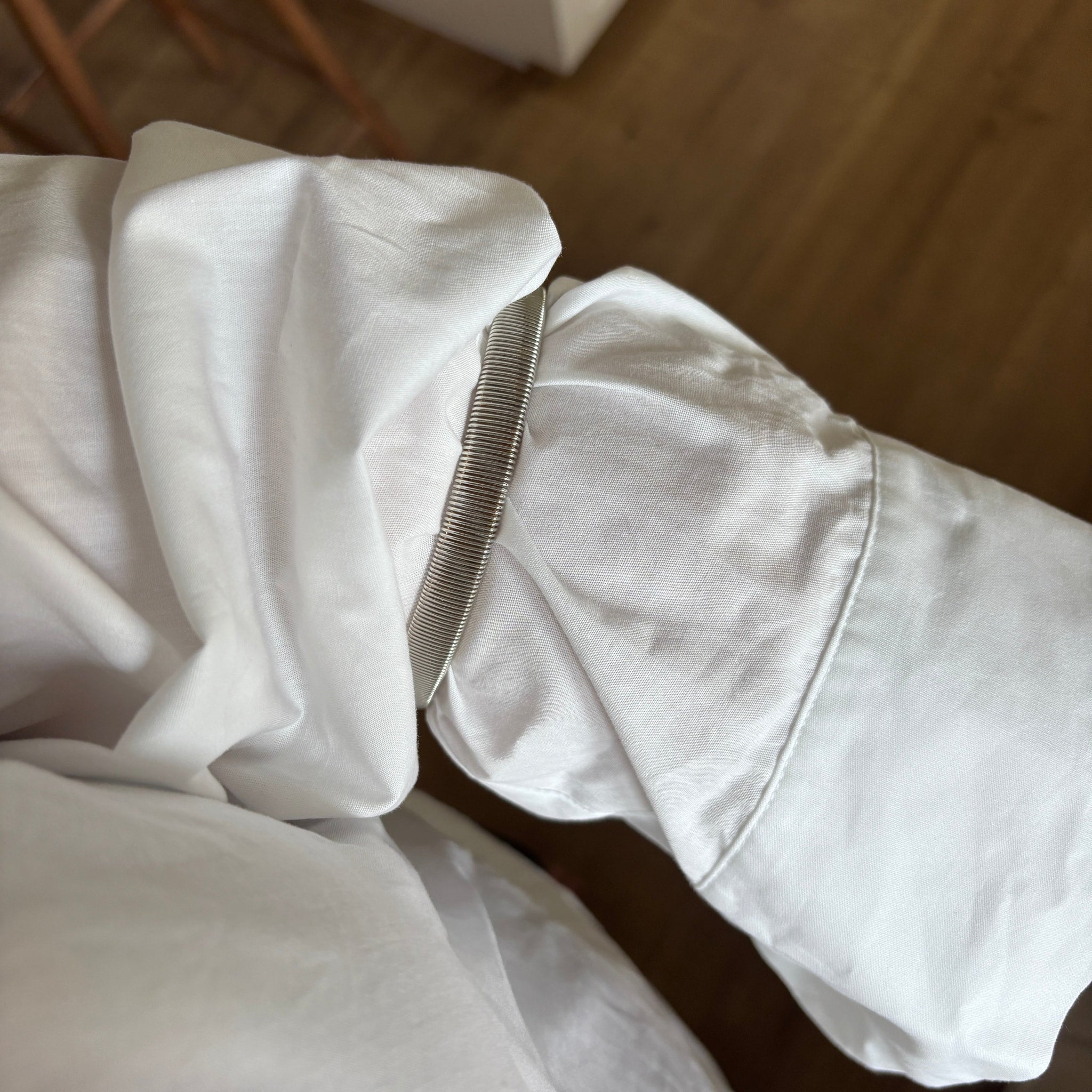 Sleeve holder i sølv sat på et opsmøget ærme af en hvid skjorte, set tæt på