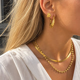 Model bærer Sunny Chain Necklace halskæde i guld i lag med en anden halskæde og hvid skjorte