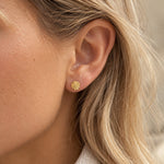 Rund ørering i guld med solmønster fra Wolff Jewelry båret i øret på model med lyst hår