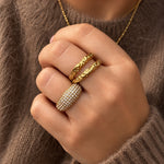 Ziko ring i guld med klare sten båret på hånden, stylet med andre guldringe og brun strik