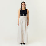 Model i hvide wide leg bukser med bælte, stylet med sort tanktop og flade sko