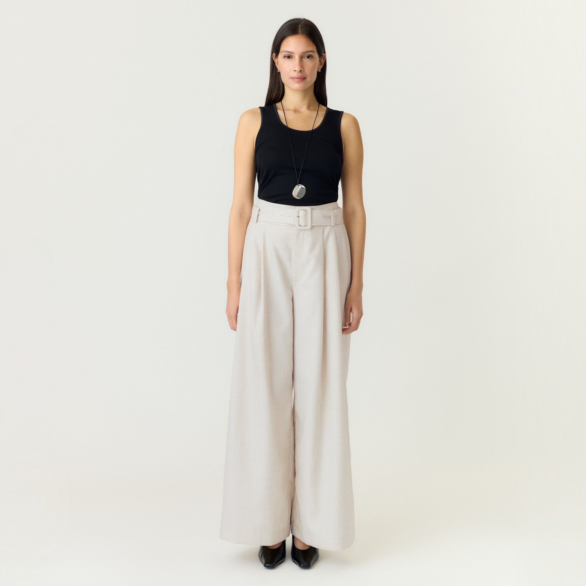 Model i hvide wide leg bukser med bælte, stylet med sort tanktop og flade sko