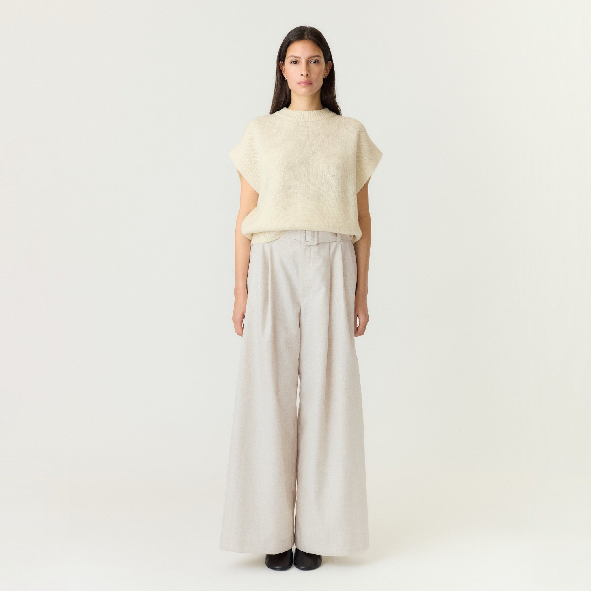 Model i hvide wide leg bukser med høj talje, stylet med en løs strikvest