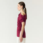 Model i pink off shoulder top set fra siden med rynket ærme og slids i siden