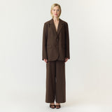 Model i brune wide leg bukser fra YAS stylet med en brun blazer, set forfra i fuld længde